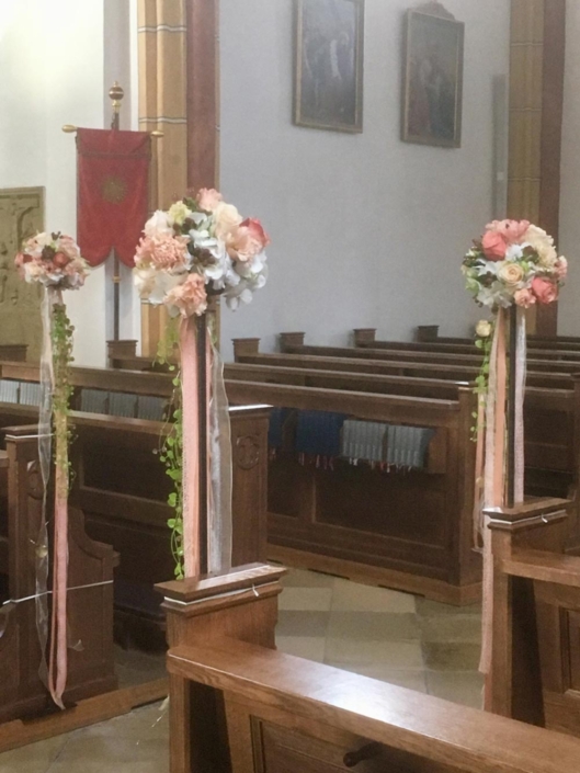 Mit Blumensträußen dekorierte Kirchenbänke für eine Hochzeitsfeier.