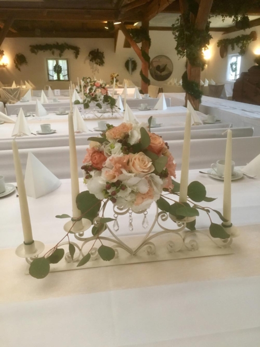 Mit Blumen dekorierte Kerzenhalter als Tischdeko für eine Hochzeitsfeier.