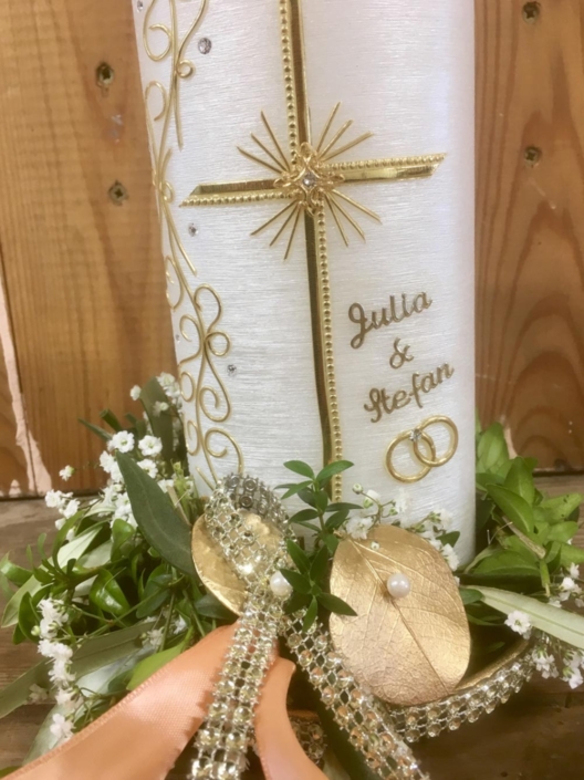 Mit Buchs und goldenen Elementen dekorierte Hochzeitskerze.